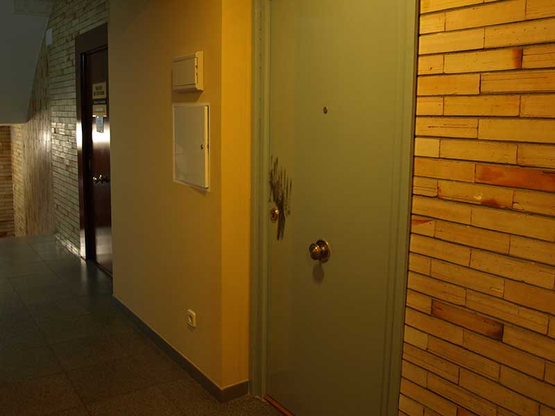 La puerta del local contiguo al taller, en los que la policía buscó huellas o indicios y detalle de la misma puerta.