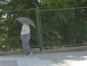 Un hombre trata de protegerse del sol con un paraguas.